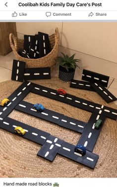 a toy car race track made out of cardboard with cars on it and two planters in the background