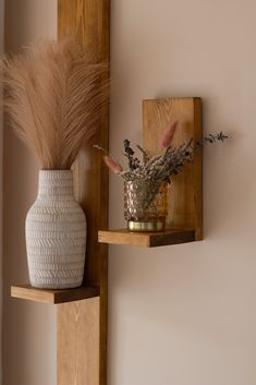 two vases with dried flowers on wooden shelves