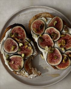 a white plate topped with sliced up figs on top of bread covered in cream cheese