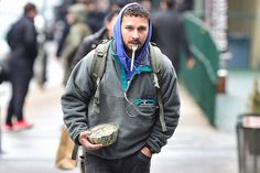 a man with a blue scarf on his head is walking down the street while holding an object in his hand