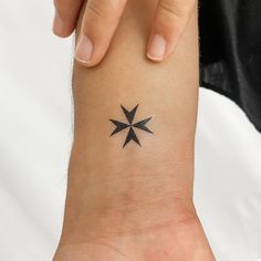 a woman's wrist with a small black star tattoo on the left side of her arm