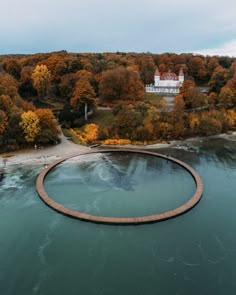 an aerial view of a lake surrounded by trees in the fall with a circular walkway