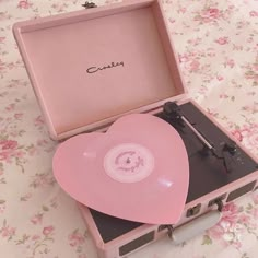 a pink record player sitting on top of a table next to a case with the lid open