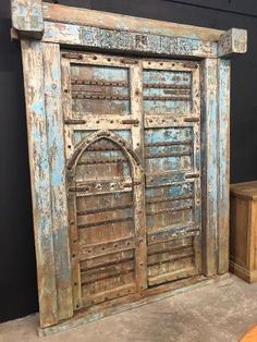 an old wooden door sitting on top of a floor next to a table and chair