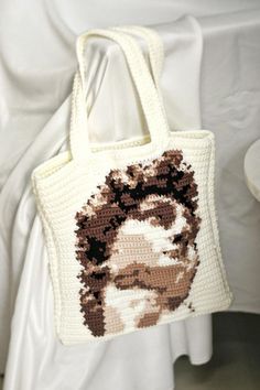 a crocheted bag with a portrait of a man on the front and side