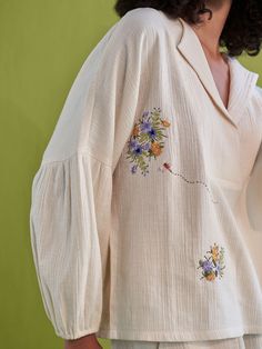 Relaxed fit, long puff sleeve, v-neck shirt crafted in double gauze organic cotton fabric that's embroidered with botanic-inspired motifs. This classic, staple shirt is so versatile and can be endlessly mixed-and-matched to create a fresh outfit each time you put it on. Techniques Used: Hand Embroidery. #cuteeverydayoutfits #prettyoutfits #falloutfitswomen #shirtdesign #topsforwomen Spring V-neck Blouse With Chikankari Embroidery, Spring Linen Top With Chikankari Embroidery, V-neck Shirt With Floral Embroidery For Spring, Spring V-neck Embroidered Shirt, Spring Linen Shirt With Floral Embroidery, Cotton Shirt With Gathered Sleeves For Spring, Linen Tops With Floral Embroidery For Fall, Floral Embroidered Linen Tops For Fall, Fall Linen Tops With Floral Embroidery