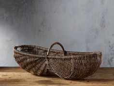 a wicker basket sitting on top of a wooden table next to a gray wall