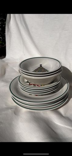 a stack of plates sitting on top of a white cloth covered table next to a vase