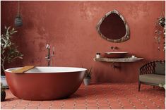 a red bath tub sitting next to a sink in a bathroom under a round mirror