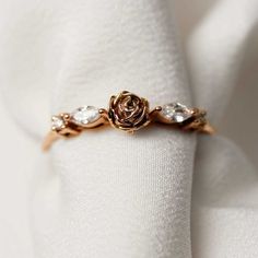 a rose ring on top of a white napkin with three small stones in the center