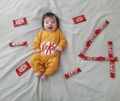 a baby laying on top of a bed covered in candy bar wrappers and laughing