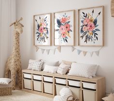 a room with three pictures hanging on the wall and two stuffed giraffes