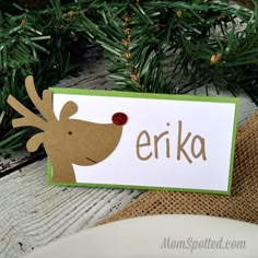 a close up of a christmas card on a table with pine branches in the background