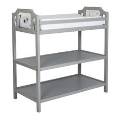 a gray and white baby crib with two shelves on the bottom, one shelf is empty