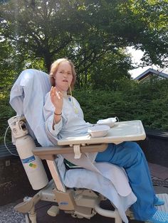 a woman sitting in a chair with her hand up to her face while eating food