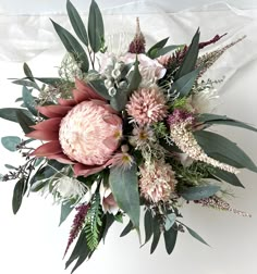 an arrangement of flowers and greenery on a white background