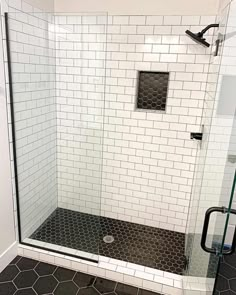 a bathroom with black and white tiles on the floor, shower stall door and toilet