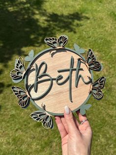 a person holding up a wooden sign with the word beth in it's center