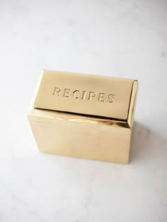 a gold box with the word recipes written on it sitting on a marble countertop