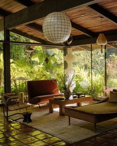 a living room filled with lots of furniture and plants on top of the floor next to large windows