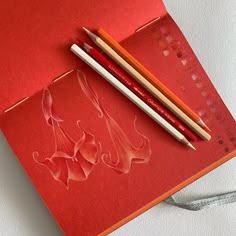 two pencils sitting on top of a red card