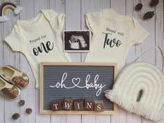 two baby onesuits and other items on a white wooden background with pine cones