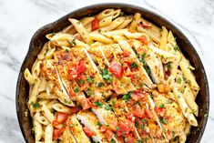 a skillet filled with chicken, pasta and tomatoes