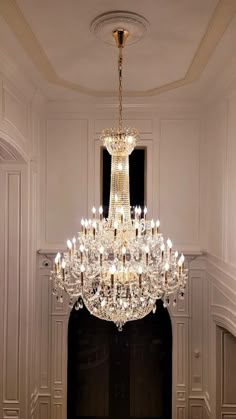 a chandelier hanging from the ceiling in a room with white walls and flooring