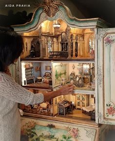 a woman is looking at an elaborate cabinet