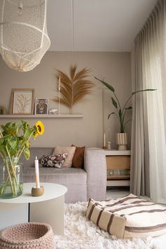 a living room filled with furniture and flowers on top of a white table next to a window