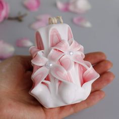 a hand holding a small pink and white object