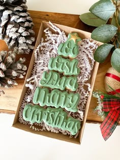 some cookies are in a box on a table next to pine cones and christmas decorations