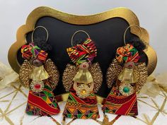 three african dolls are sitting in front of a black background with gold trimmings