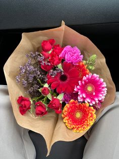 a bouquet of colorful flowers sitting in the back seat of a car on a sunny day