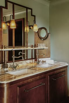 a bathroom vanity with two sinks and three lights on it's sides, in front of a mirror