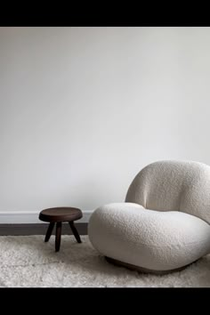 a white chair sitting on top of a rug next to a wooden footstool