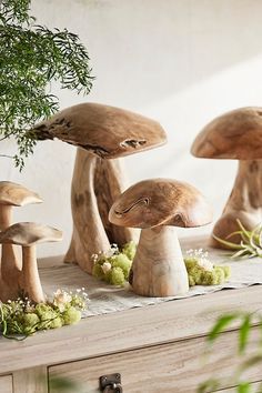 three mushrooms sitting on top of a table next to a potted plant and an old dresser