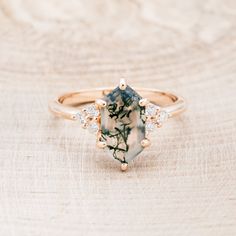 an image of a ring with flowers and stones on the front, sitting on top of a wooden surface