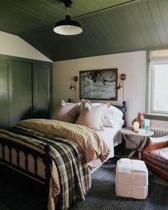 a bed room with a neatly made bed next to a chair and table in front of a window