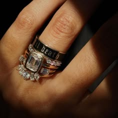 a woman's hand with two rings on it and an engagement ring in the middle