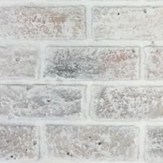 an old brick wall with white paint on it