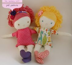 two dolls sitting next to each other on a white surface with a pink sign above them