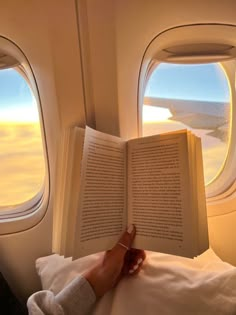 someone is reading a book on an airplane