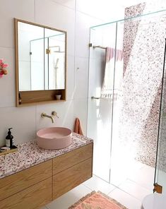 a bathroom with a sink, mirror and shower in it's center area that has pink rugs on the floor