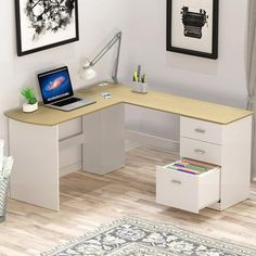 a computer desk with a laptop on top of it next to a rug and framed pictures