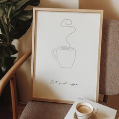 a coffee cup sitting on top of a table next to a framed drawing