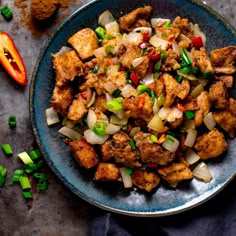 a blue plate topped with tofu and onions next to some sliced up peppers on a table