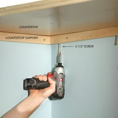 a person holding a drill and tool in front of a shelf with instructions on how to use it