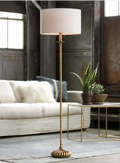 a living room with a white couch and a gold floor lamp in the middle of it