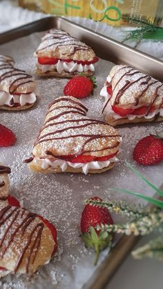 strawberry shortcakes with chocolate drizzle and strawberries on a baking sheet